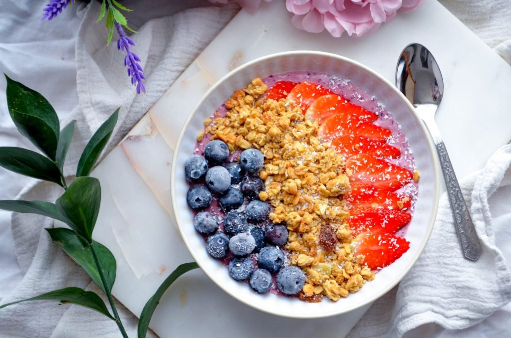 Berry smoothie breakfast bowl with berries , granola yoghurt and coconut