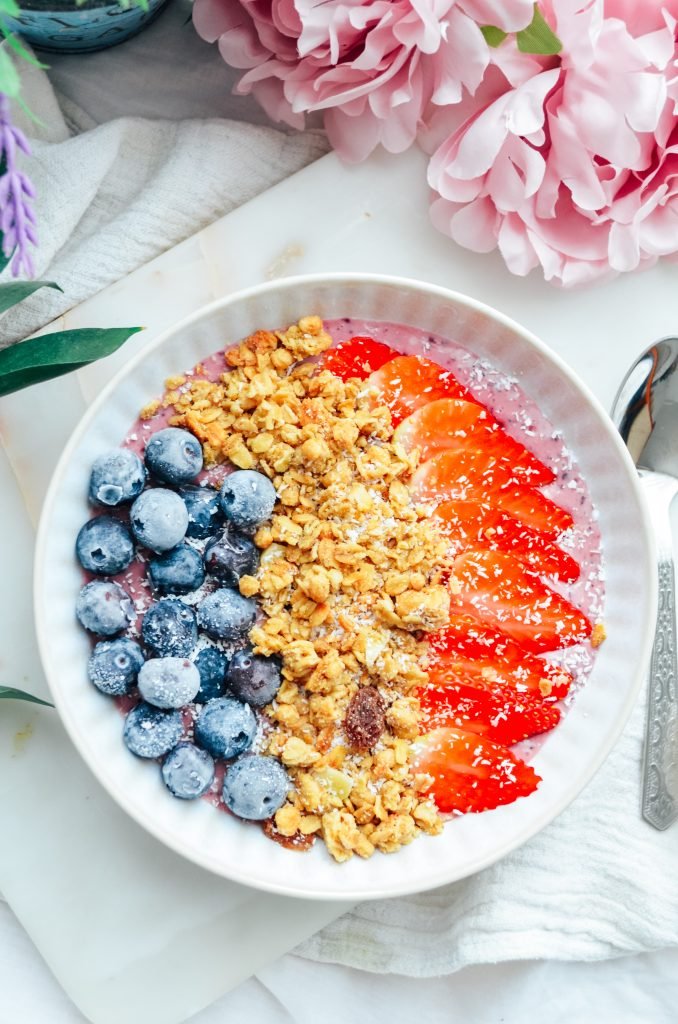 Berry smoothie breakfast bowl with berries , granola yoghurt and coconut