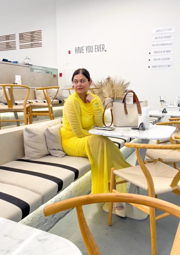 A woman in a Beautiful yellow dress sitting in an aesthetic coffee shop in Dubai