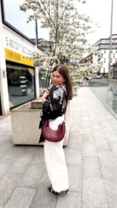 Carey Crescent Hobo Bag in Burgundy worn by Colour me in Style with white jeans and black top.