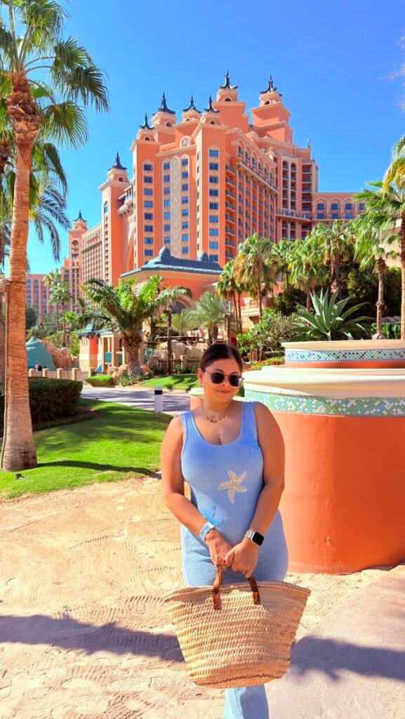 A woman in a blue beach dress standing in front of Atlantis the Palm