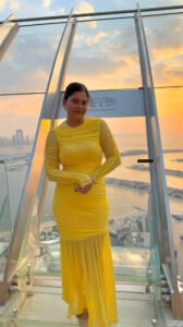 A woman in a yellow maxi dress standing at the view at the palm