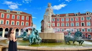A woman wearing a backless black dress standing in front of a fountain in Nice France.
