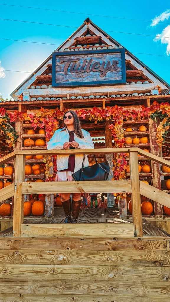 Pooja from colour me in style standing in front of the Tulleys pumpkin background.