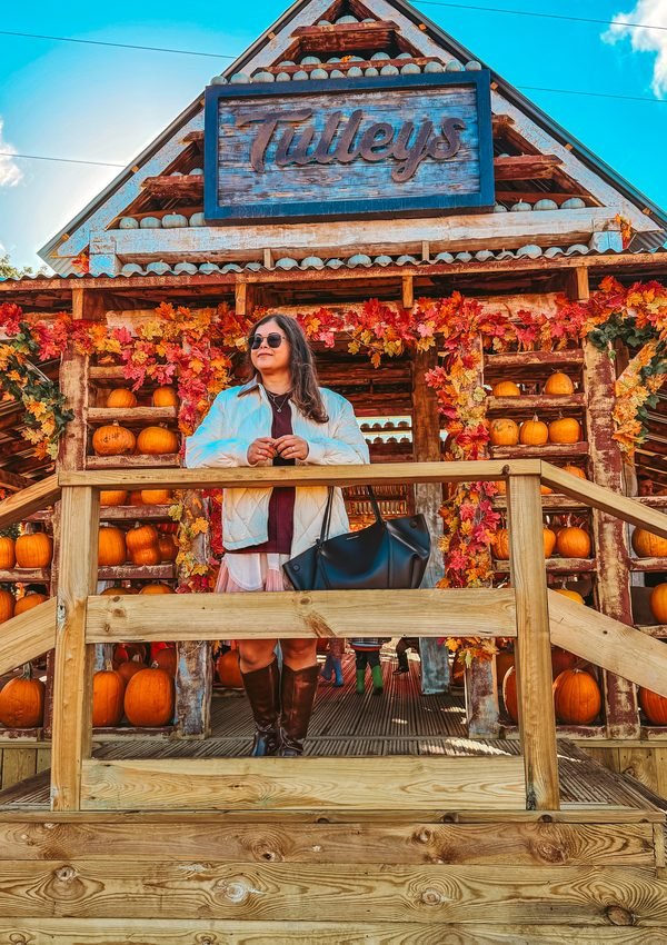Pooja from Colour me in style standing around a pumpkin decoration in Tulleys farm.